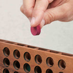 Main plaçant un jeton dans la grille du Puissance 4 en bois