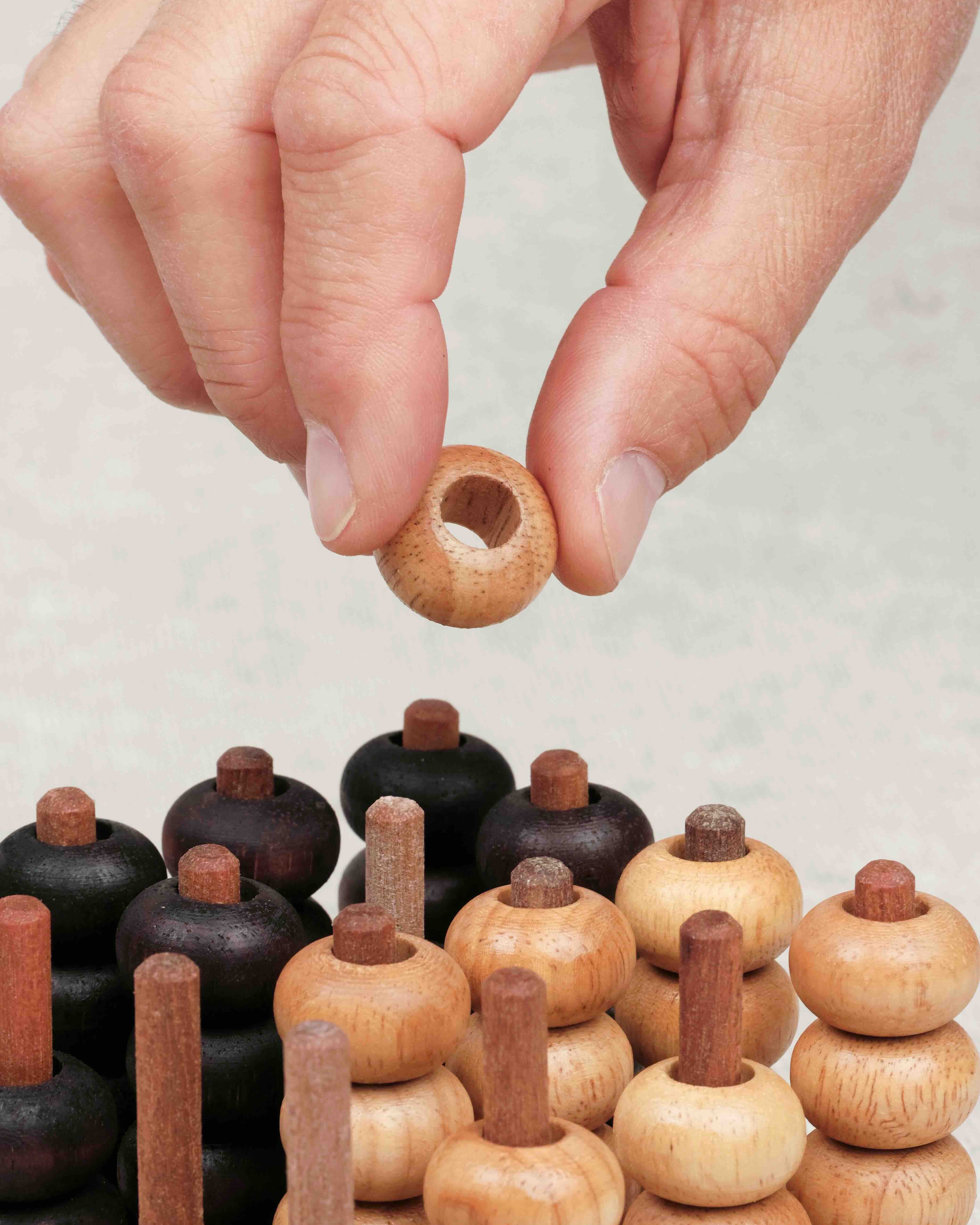 Main plaçant un pion clair sur le plateau 3D