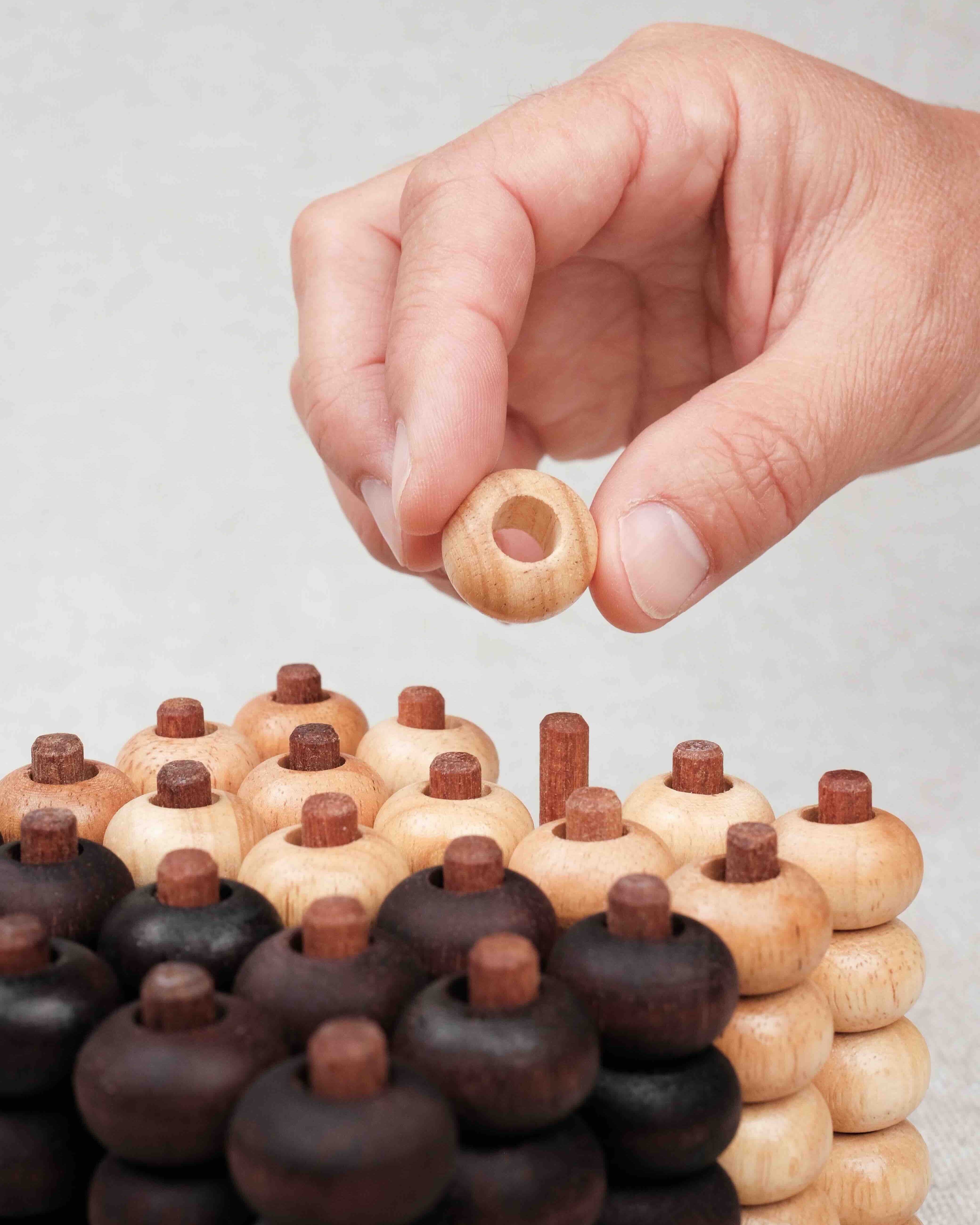 Main plaçant un pion sur la grille 3D du Puissance 5