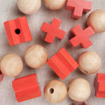 Gros plan sur les pièces rouges et boules en bois du Morpion 3D