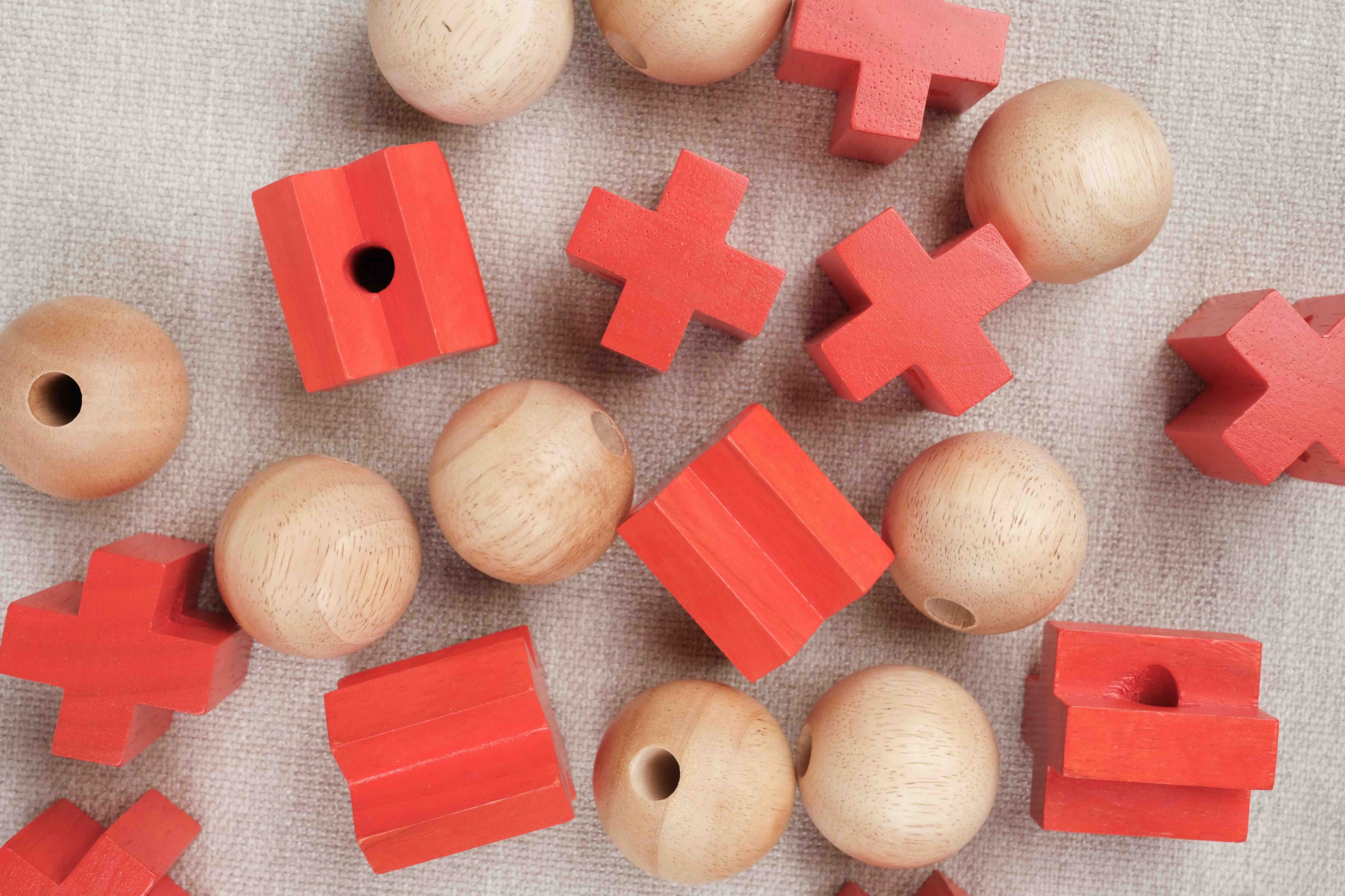 Gros plan sur les pièces rouges et boules en bois du Morpion 3D