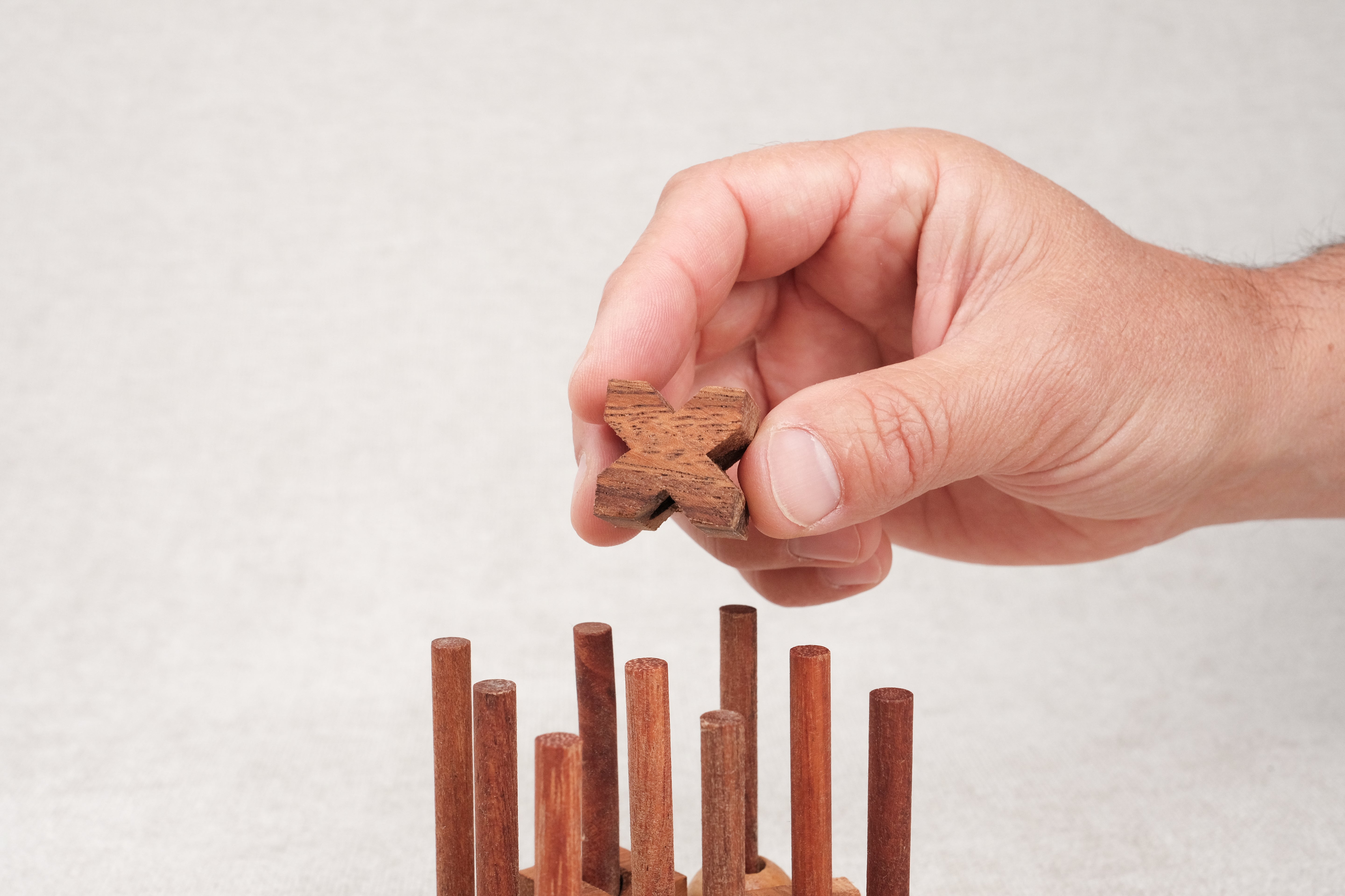 Main plaçant une croix en bois sur le plateau Morpion 3D M