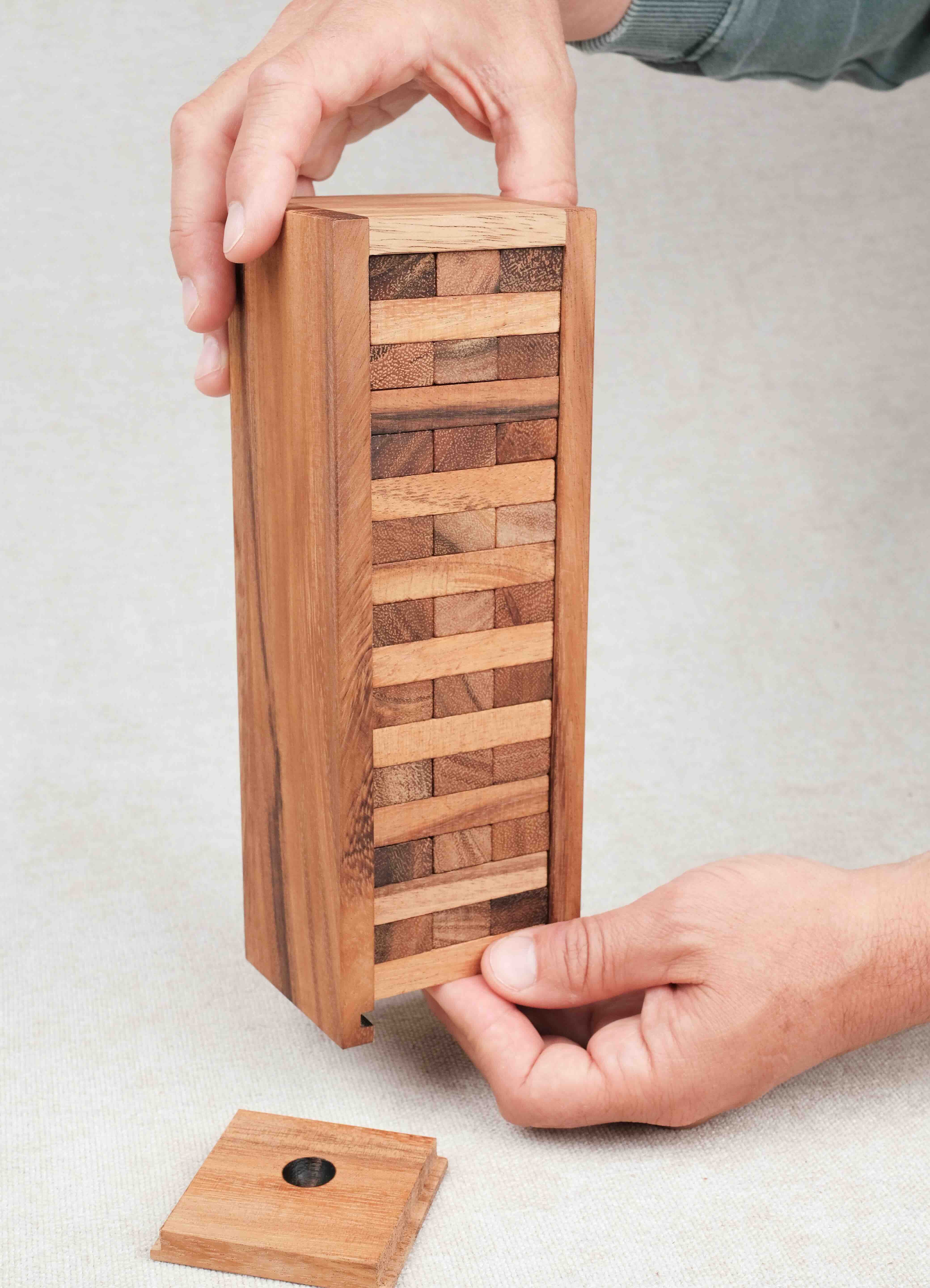 Mains formant la tour grace au coffret de rangement Jenga bois taille moyenne