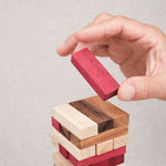 Joueur retirant un bloc rouge du Jenga couleur en bois