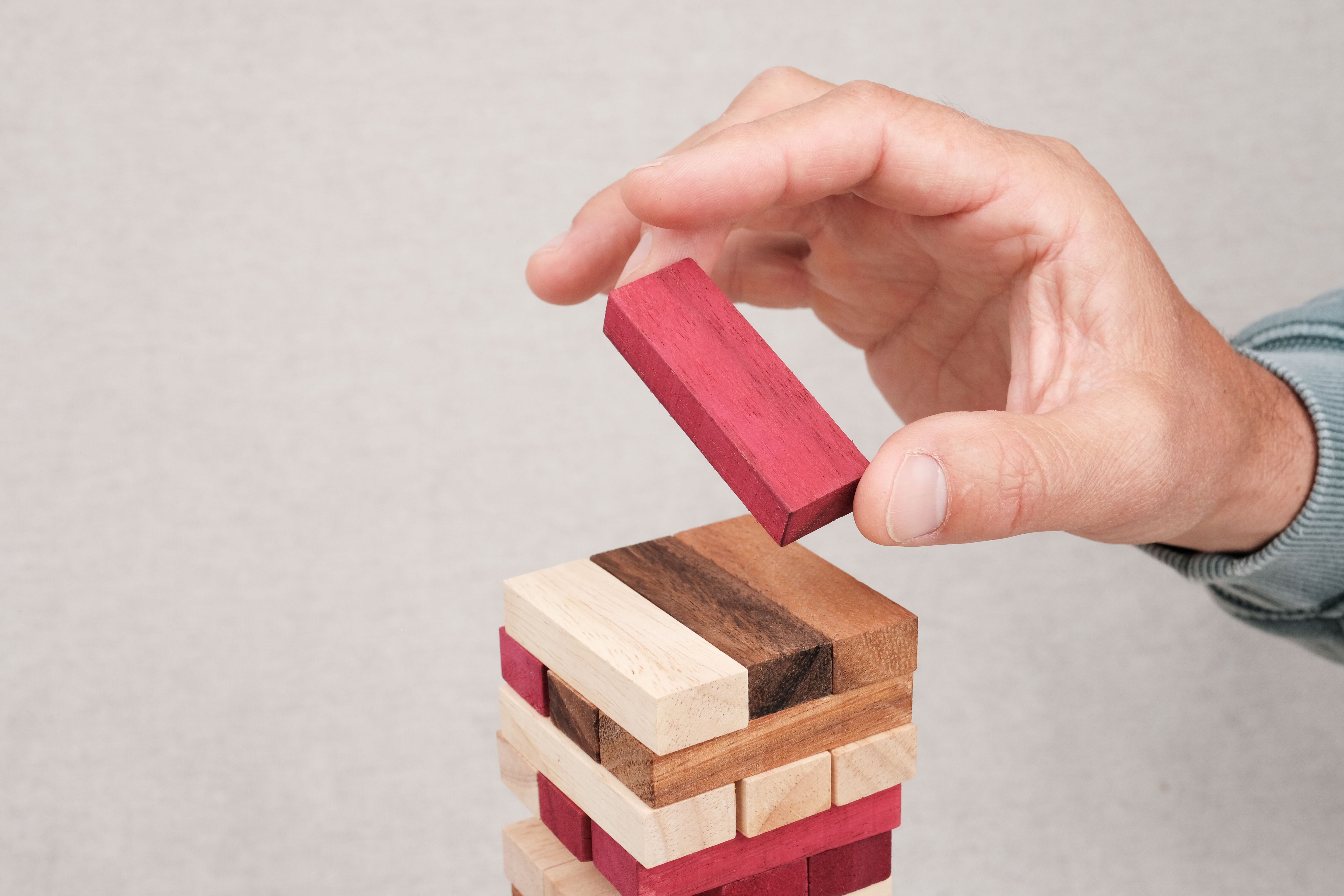 Joueur retirant un bloc rouge du Jenga couleur en bois