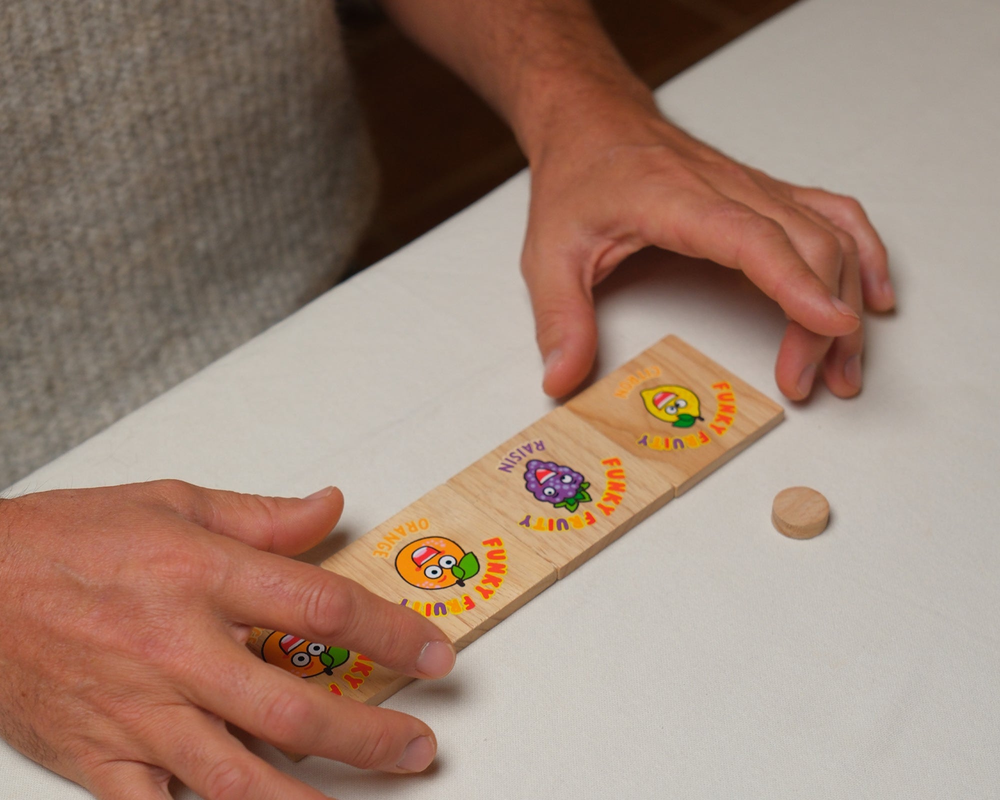 Plaquette en bois Funky Fruity avec fruits colorés tenue à la main.