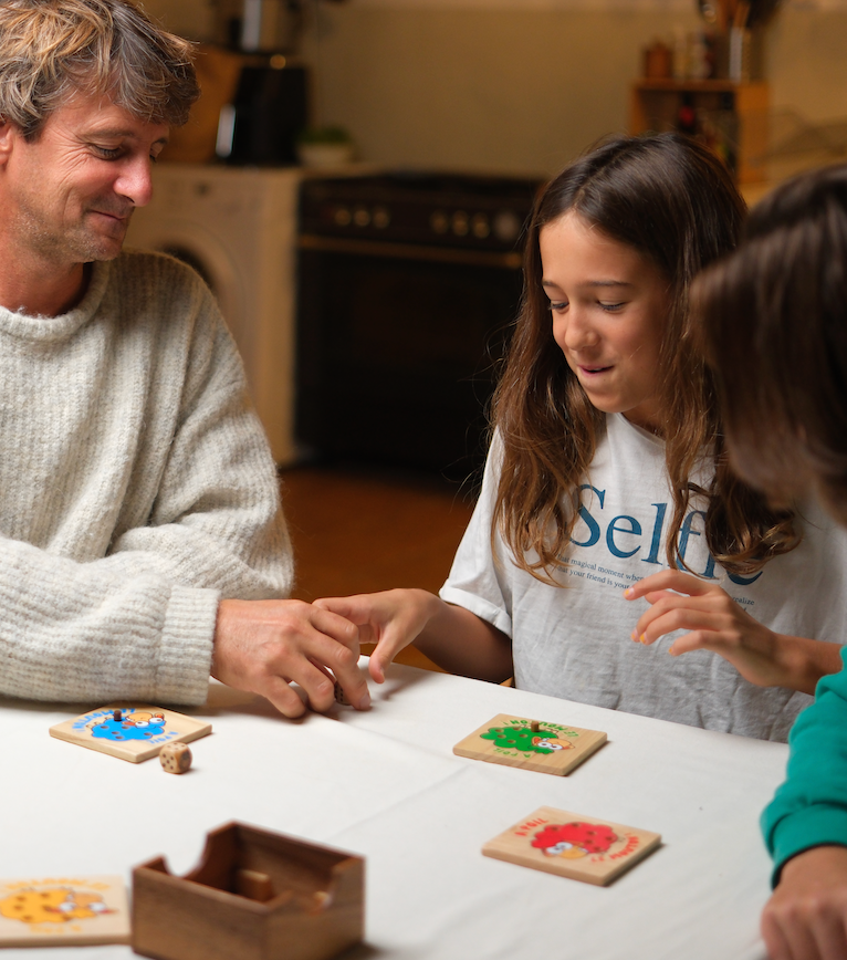 Un adulte et une adolescente jouent à un jeu de tuiles en bois autour d'une table