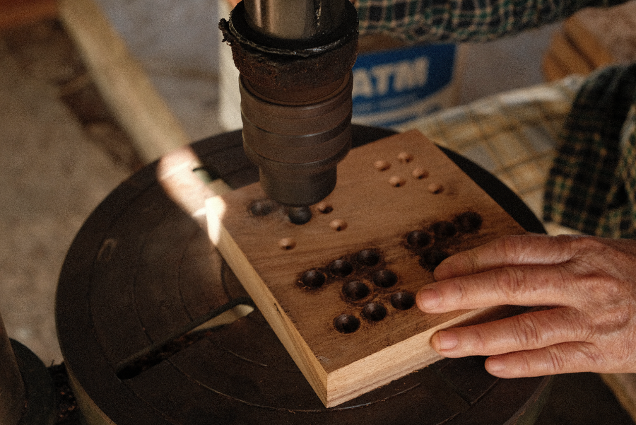 Perceuse à colonne en train de percer les trous d'un plateau de jeu de Tock en bois