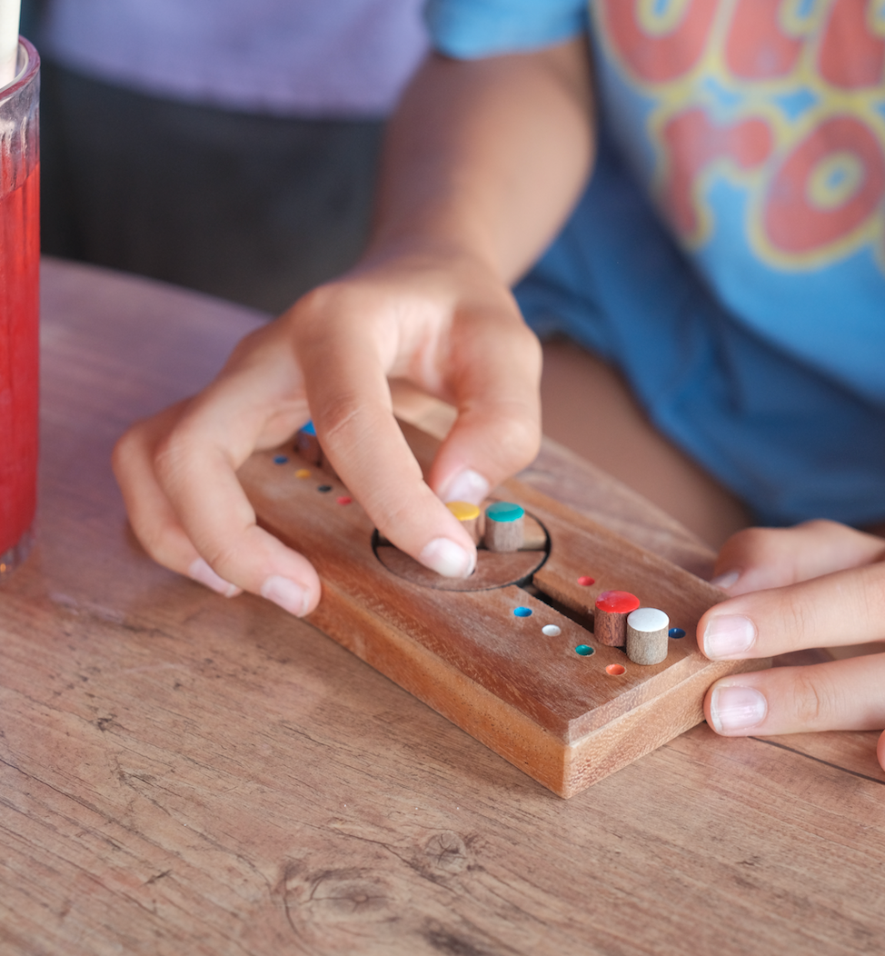 Casse-tête Code Secret en bois Jeux Faugère, mains d'enfant plaçant les pions colorés – jeu de logique, idée cadeau