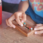 Casse-tête Code Secret en bois Jeux Faugère, mains d'enfant plaçant les pions colorés – jeu de logique, idée cadeau