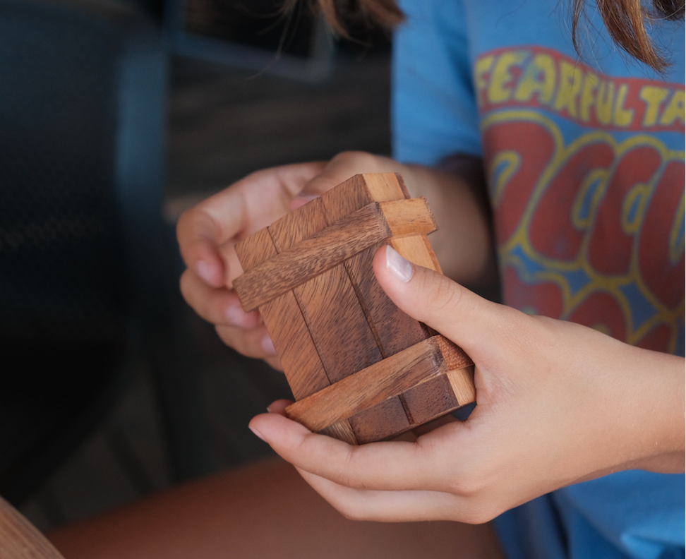 Boîte secrète S en bois Jeux Faugère tenue dans les mains d'un enfant – casse-tête adulte et enfant, idée cadeau