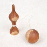 Bilboquet et boule posés côte à côte sur une surface beige
