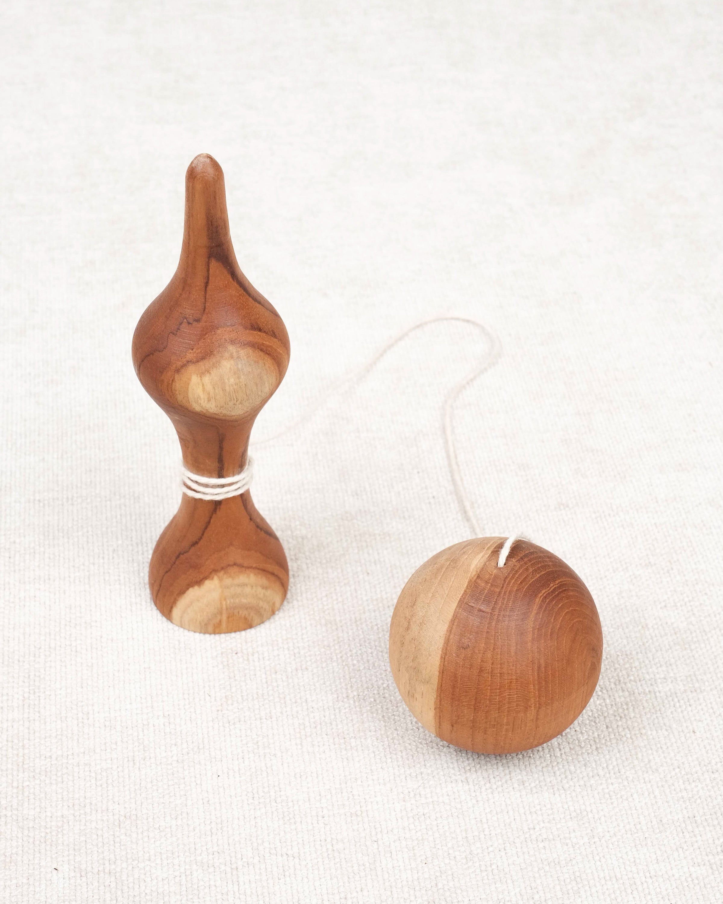 Bilboquet et boule posés côte à côte sur une surface beige