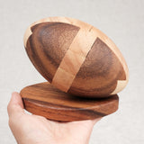Prise en main : Ballon de Rugby en bois sur socle tenu dans une main, taille L.