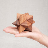 Casse-tête La Star en bois, format 8 cm, tenu dans la main.