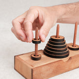 Jeu de logique La Tour de Hanoï en bois avec un joueur déplaçant un disque – Jeux Faugère