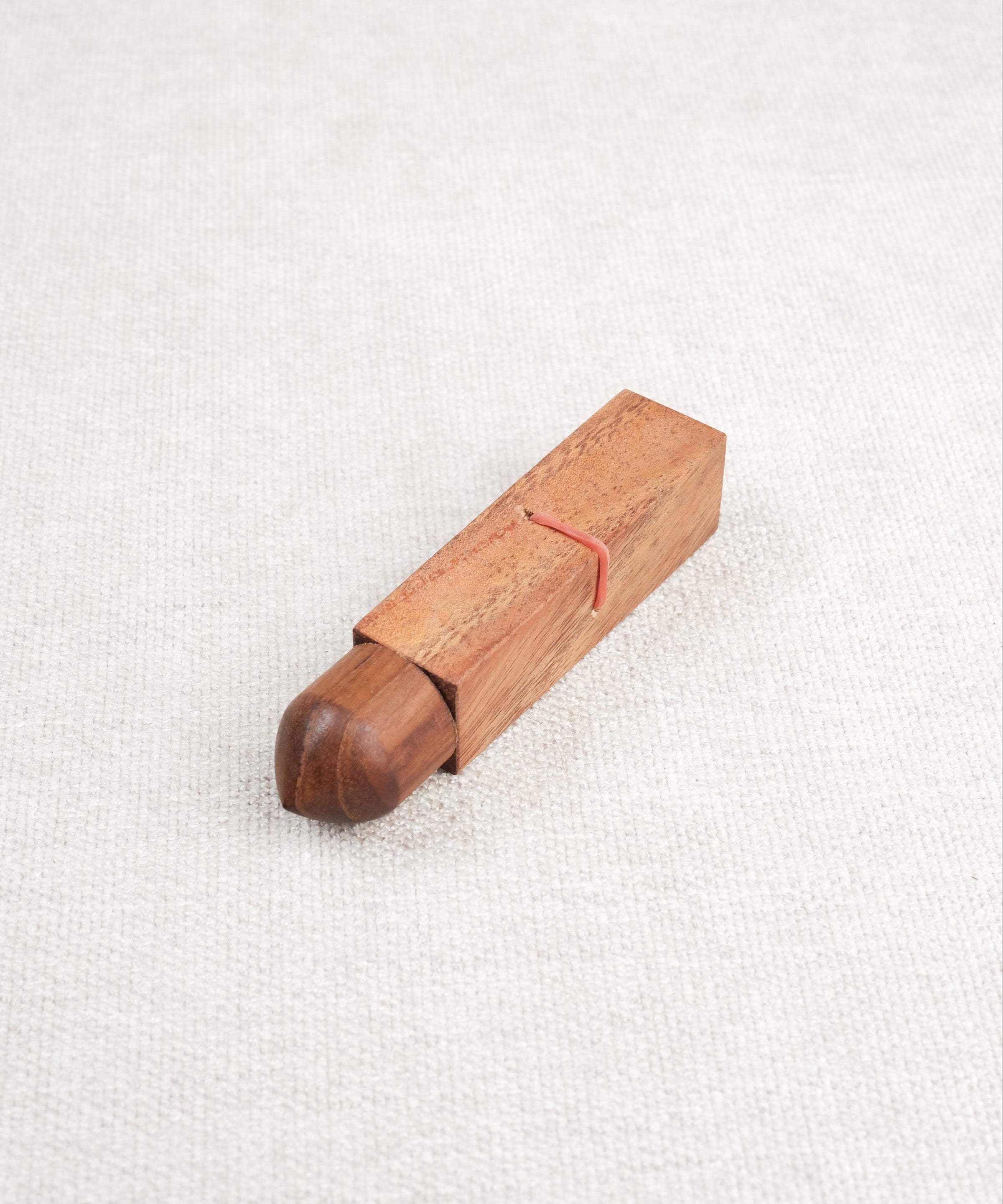 Mini casse-tête Bâtonnet du Diable en bois acacia – élastique rouge visible.