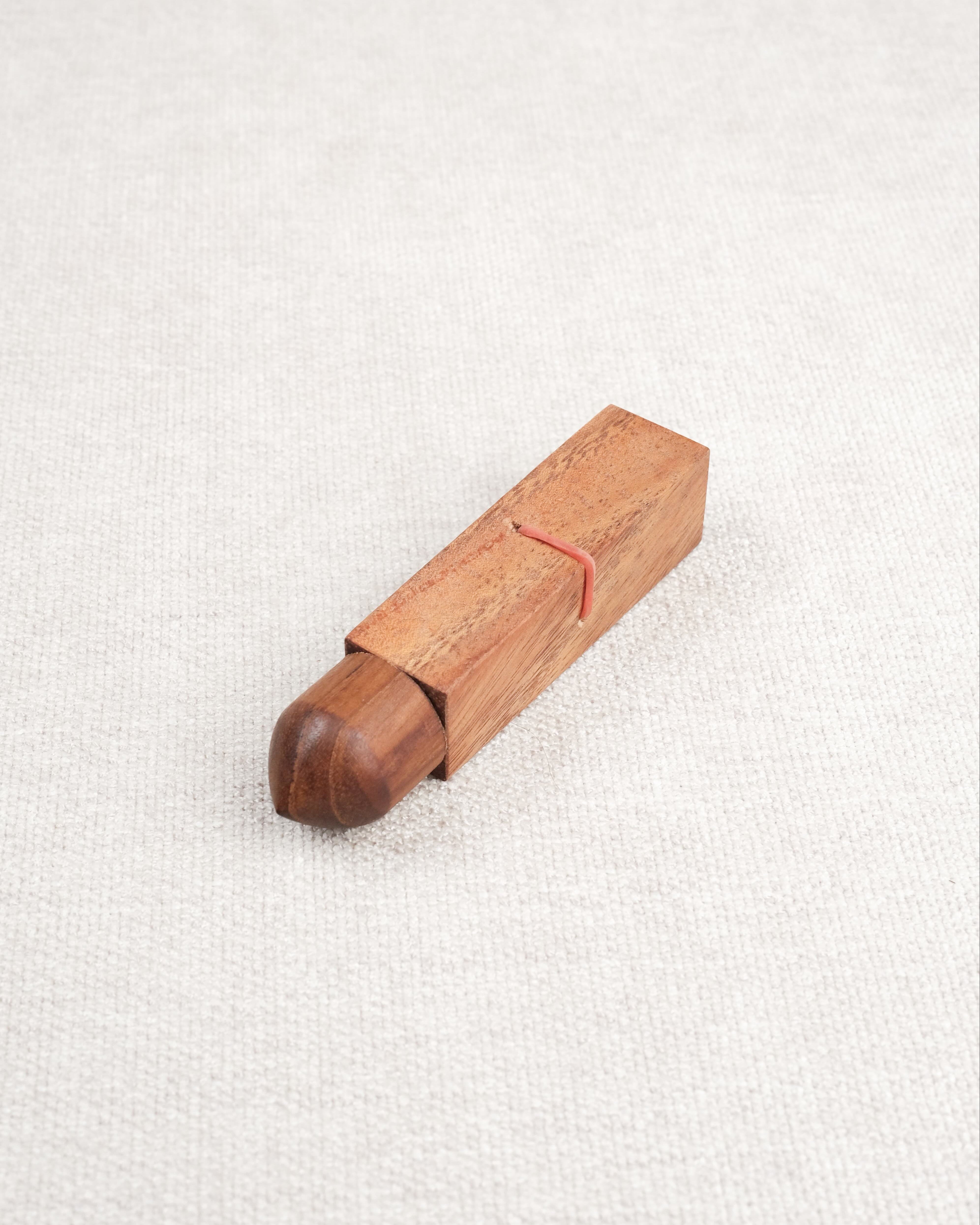 Mini casse-tête Bâtonnet du Diable en bois acacia – élastique rouge visible.