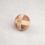 Ballon de foot en bois casse-tête posé fermé sur une surface claire.
