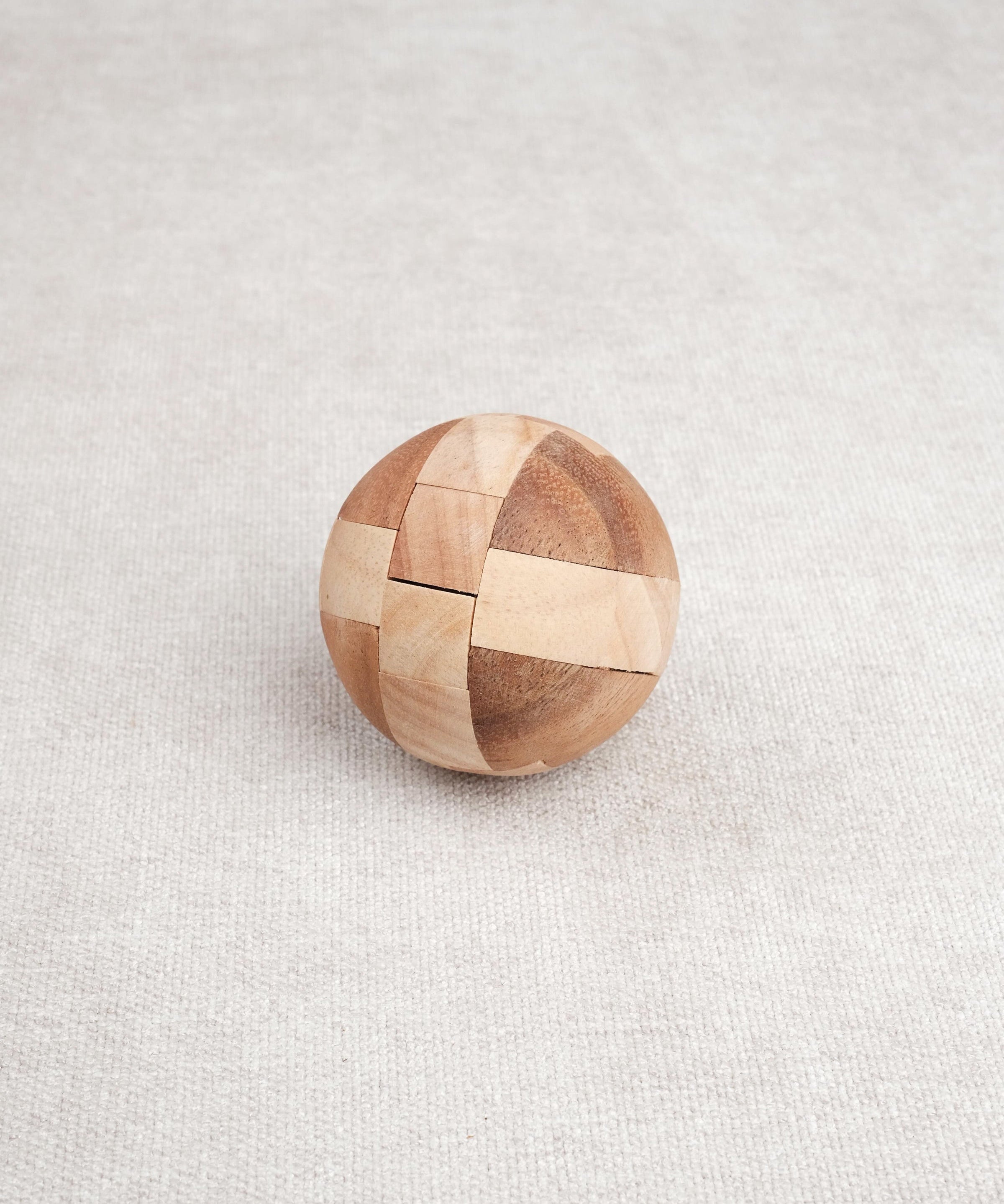 Ballon de foot en bois casse-tête posé fermé sur une surface claire.