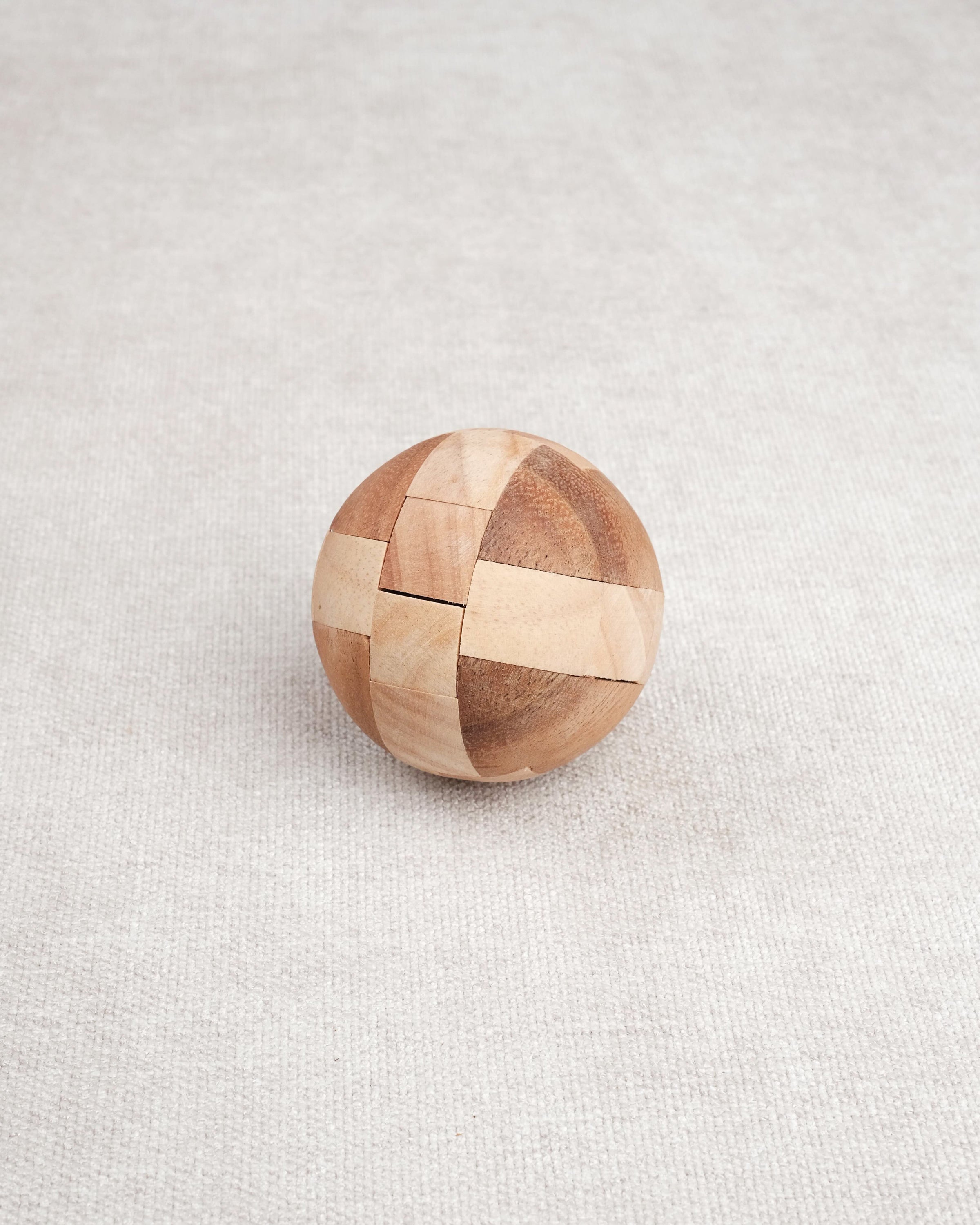 Ballon de foot en bois casse-tête posé fermé sur une surface claire.