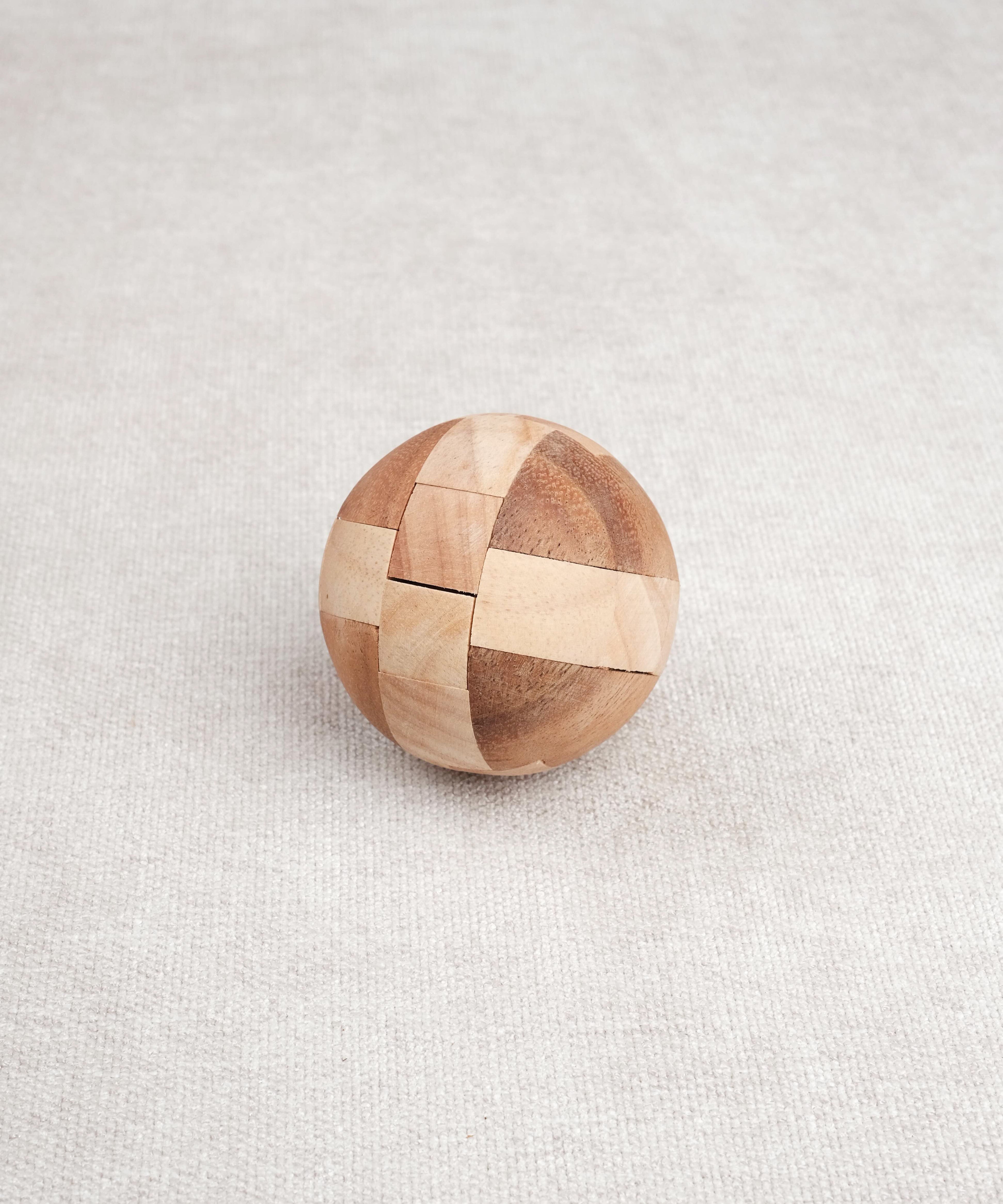 Ballon de foot en bois casse-tête posé fermé sur une surface claire.
