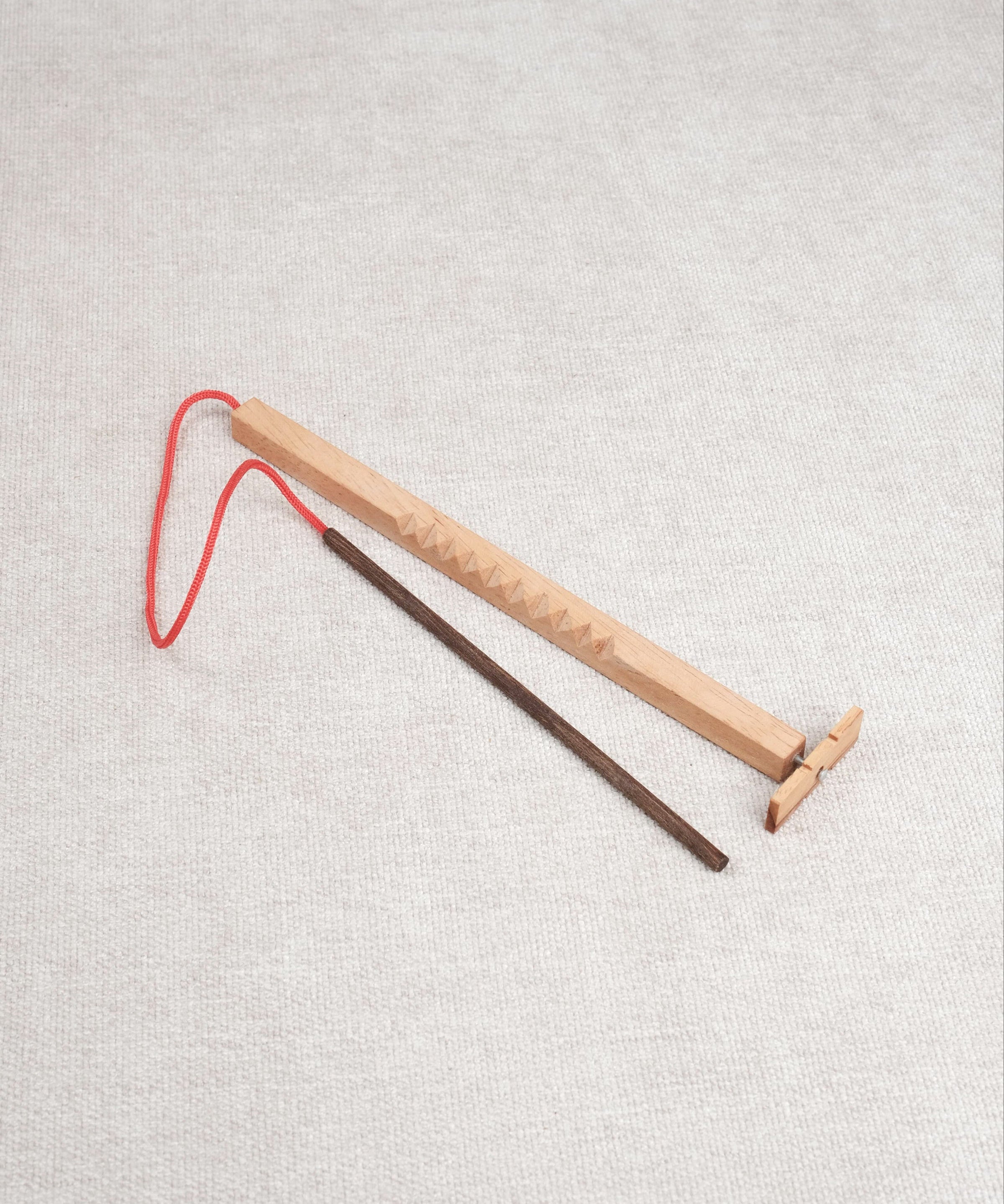 Casse-tête en bois Bozo-Bozo avec baguette et hélice reliée par une ficelle rouge.