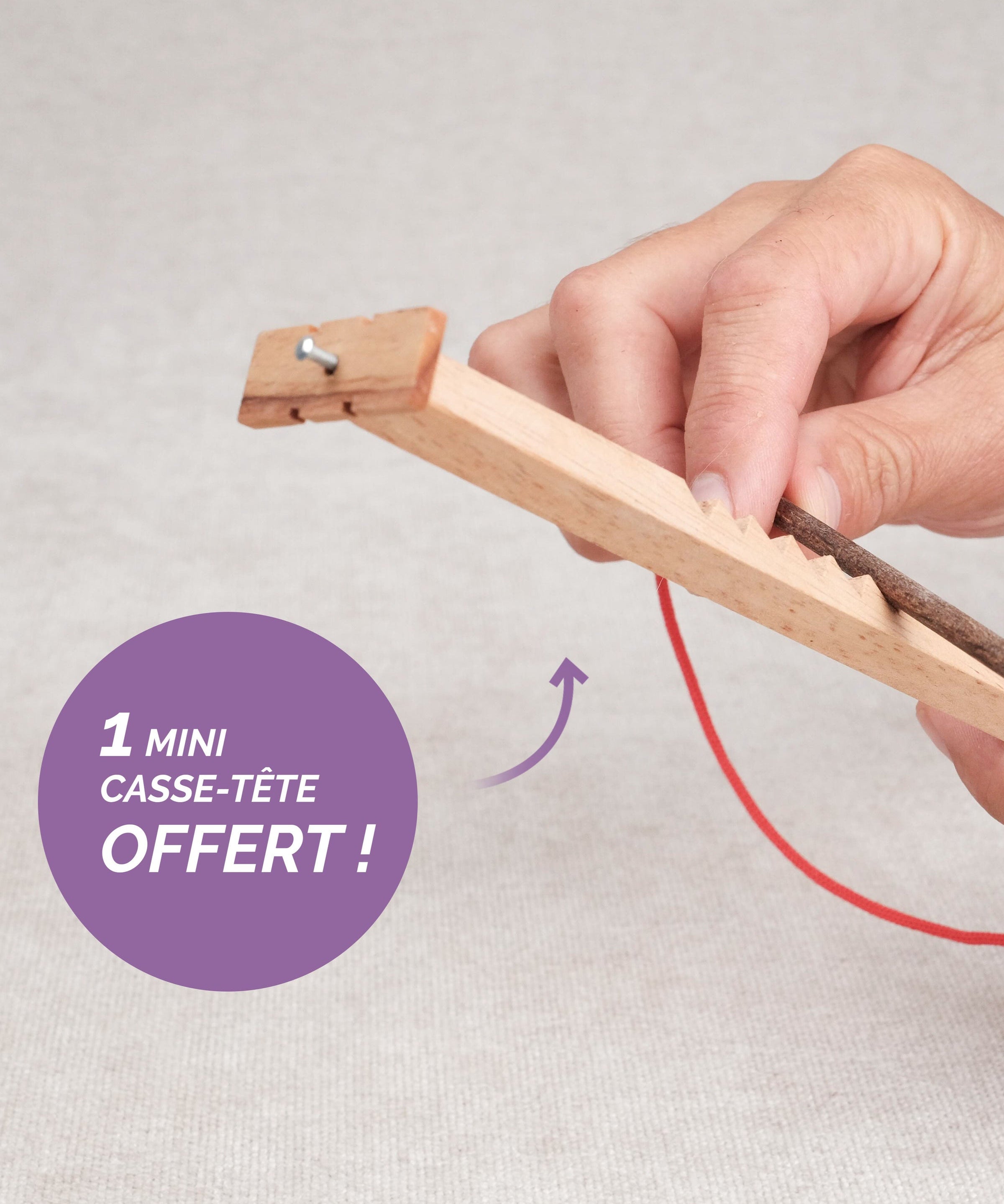 Main en train de jouer au Bozo Bozo, mini casse-tête avec ficelle rouge