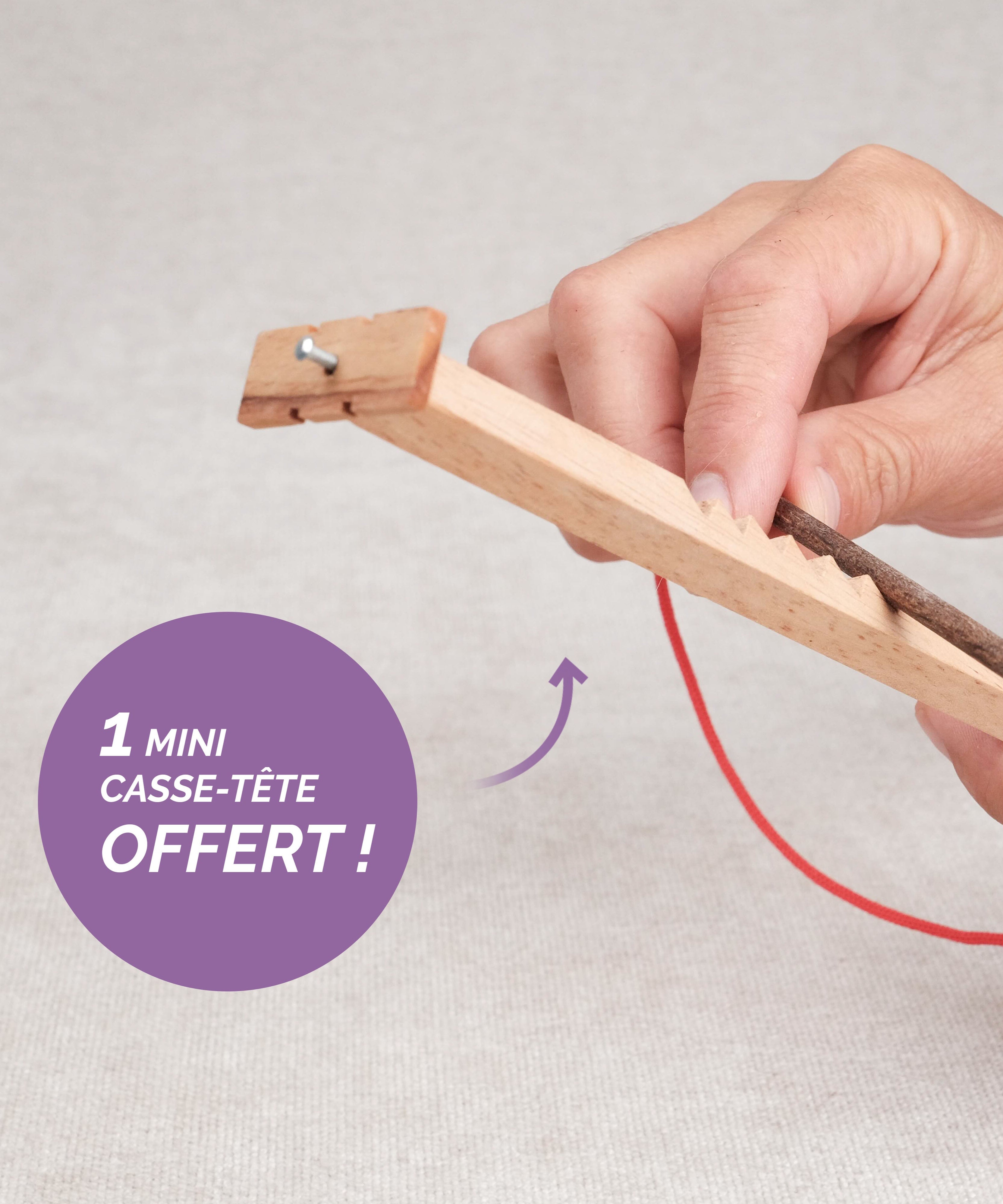 Main en train de jouer au Bozo Bozo, mini casse-tête avec ficelle rouge