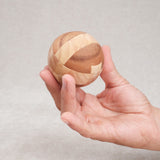 Ballon de foot en bois tenu dans une main, vue de taille compacte.