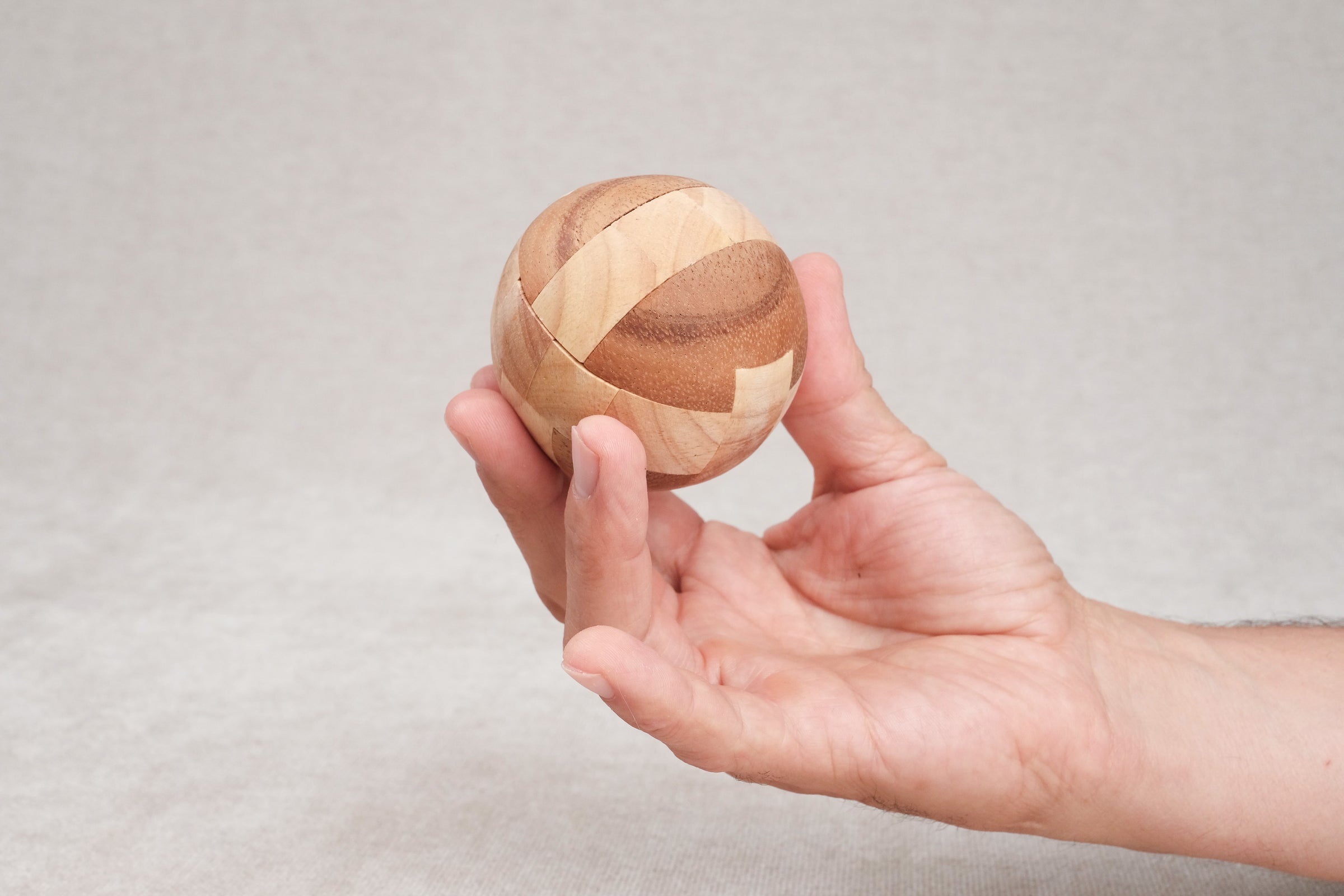Ballon de foot en bois tenu dans une main, vue de taille compacte.