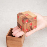 Casse-tête Dé enfermé en bois tenu en main au-dessus de son coffret – Jeux Faugère