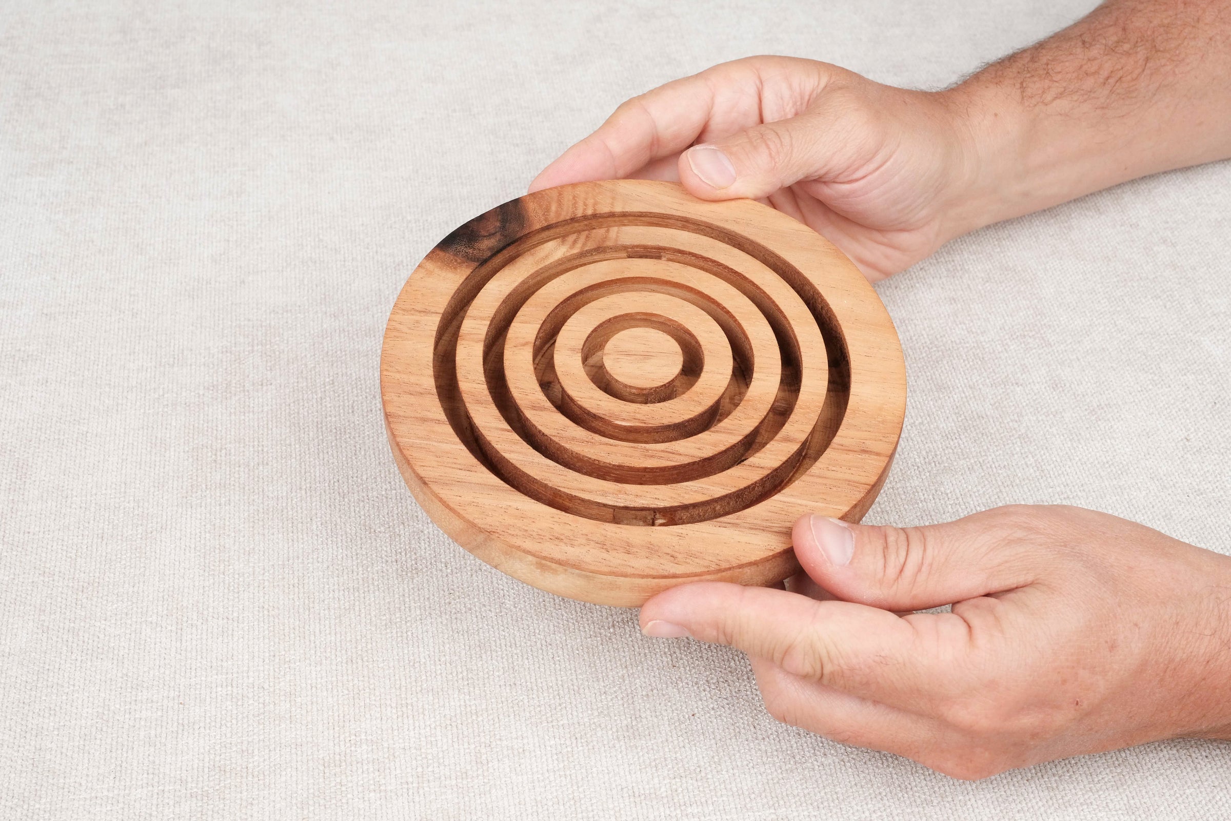Deux mains tenant le jeu d’adresse Labyrinthe en bois circulaire – Jeux Faugère