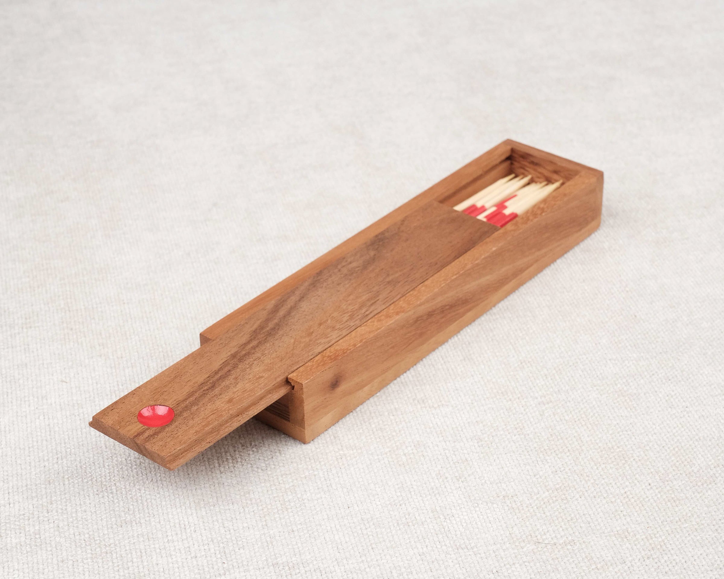 Coffret ouvert de Mikado en bois avec baguettes multicolores.