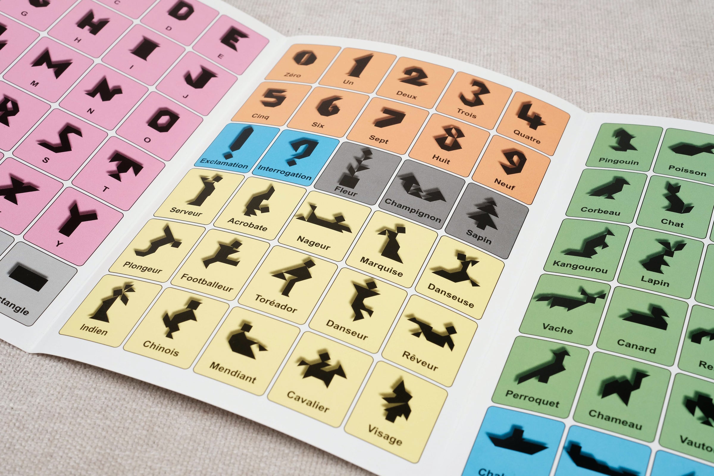 Livret ouvert avec modèles colorés de figures à reproduire – Tangram et son Livret Jeux Faugère