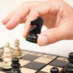 Main en train de déplacer une pièce d’échecs noire sur le plateau