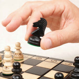 Main en train de déplacer une pièce d’échecs noire sur le plateau