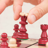 Main en train de déplacer une pièce d’échecs rouge sur le plateau