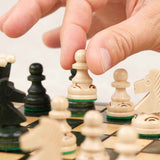Main jouant une partie sur un plateau d’échecs en bois vert