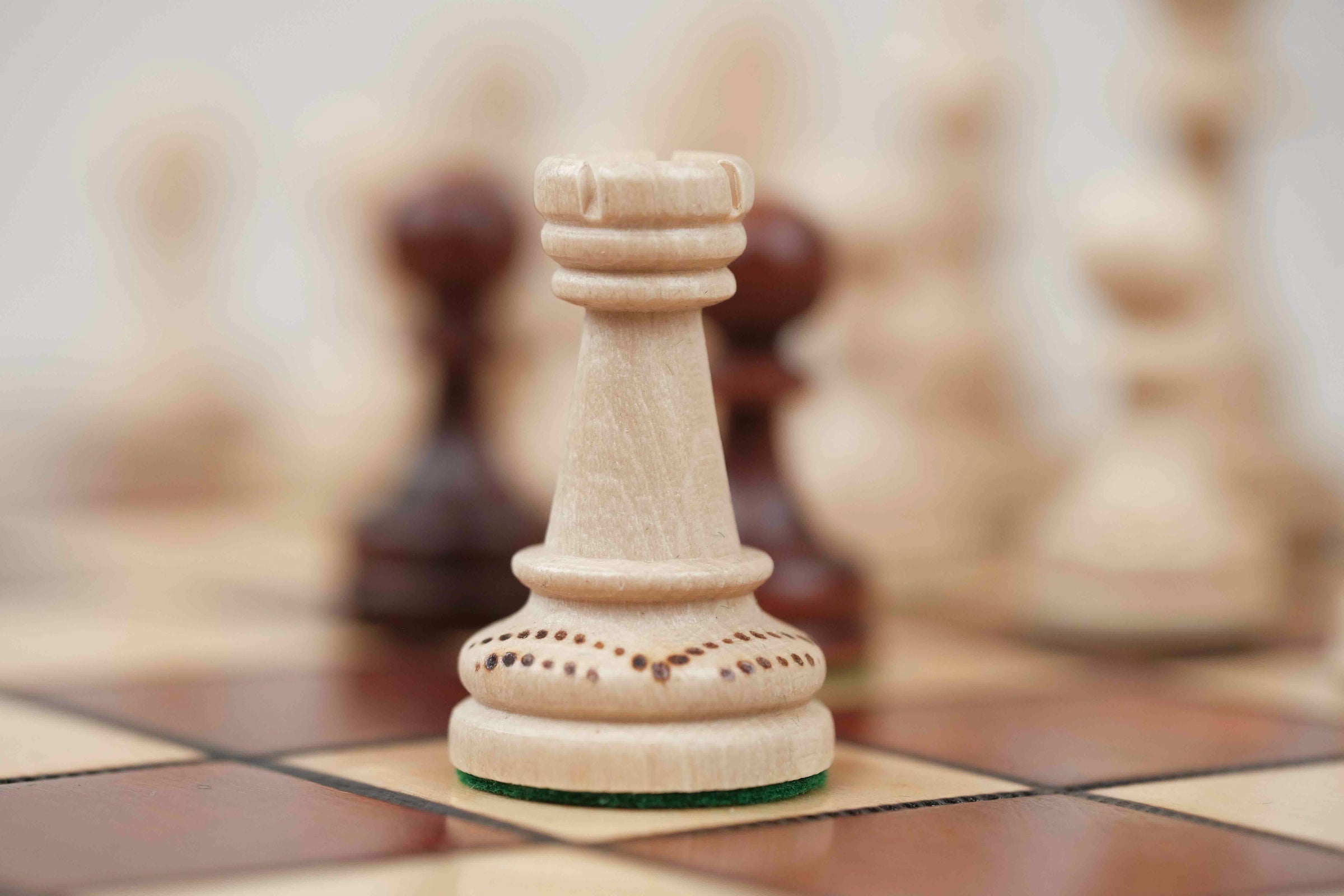 Pièce d’échecs blanche en bois avec détails sculptés sur plateau marron clair