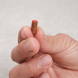 Pion rouge en bois tenu entre les doigts