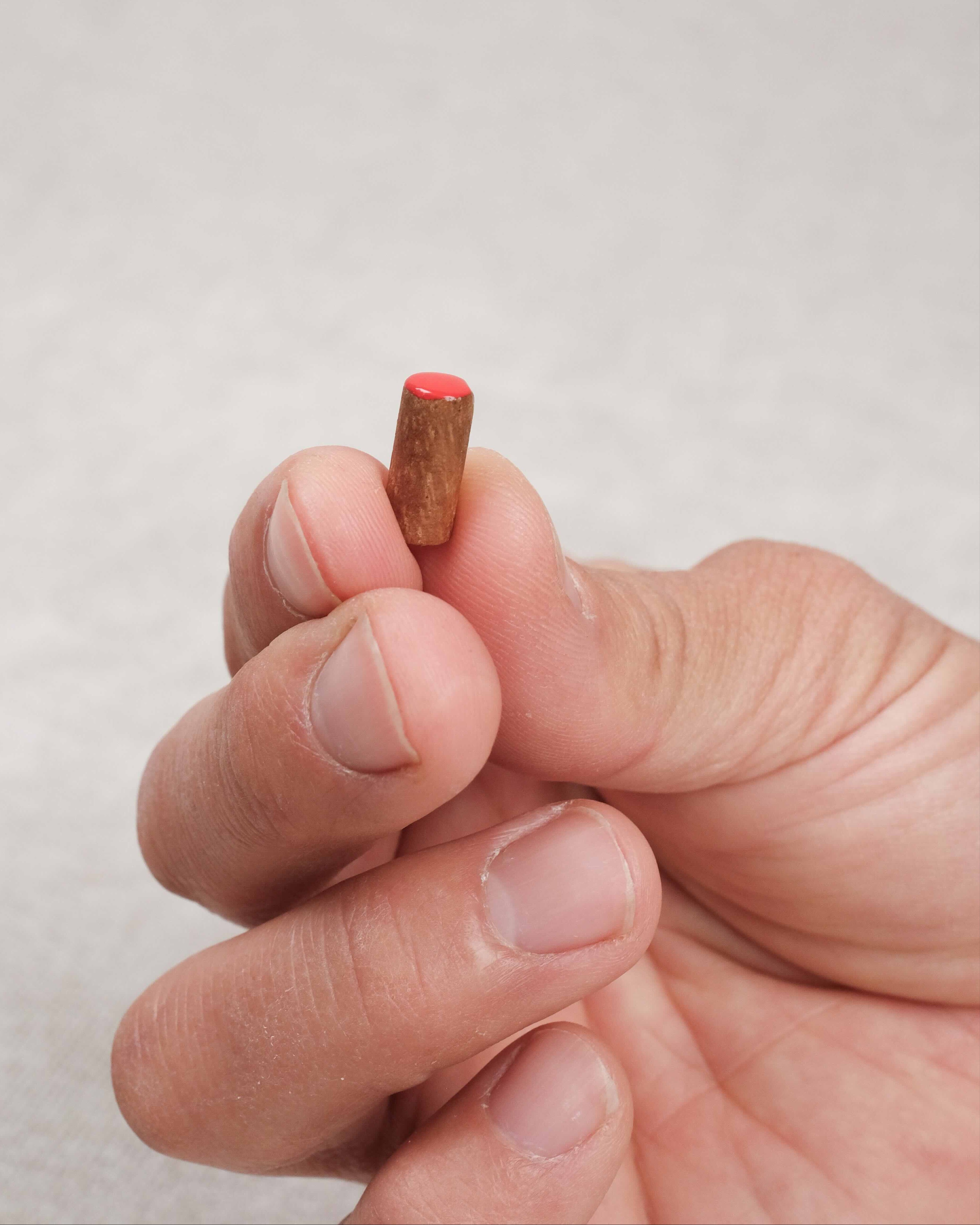 Pion rouge en bois tenu entre les doigts
