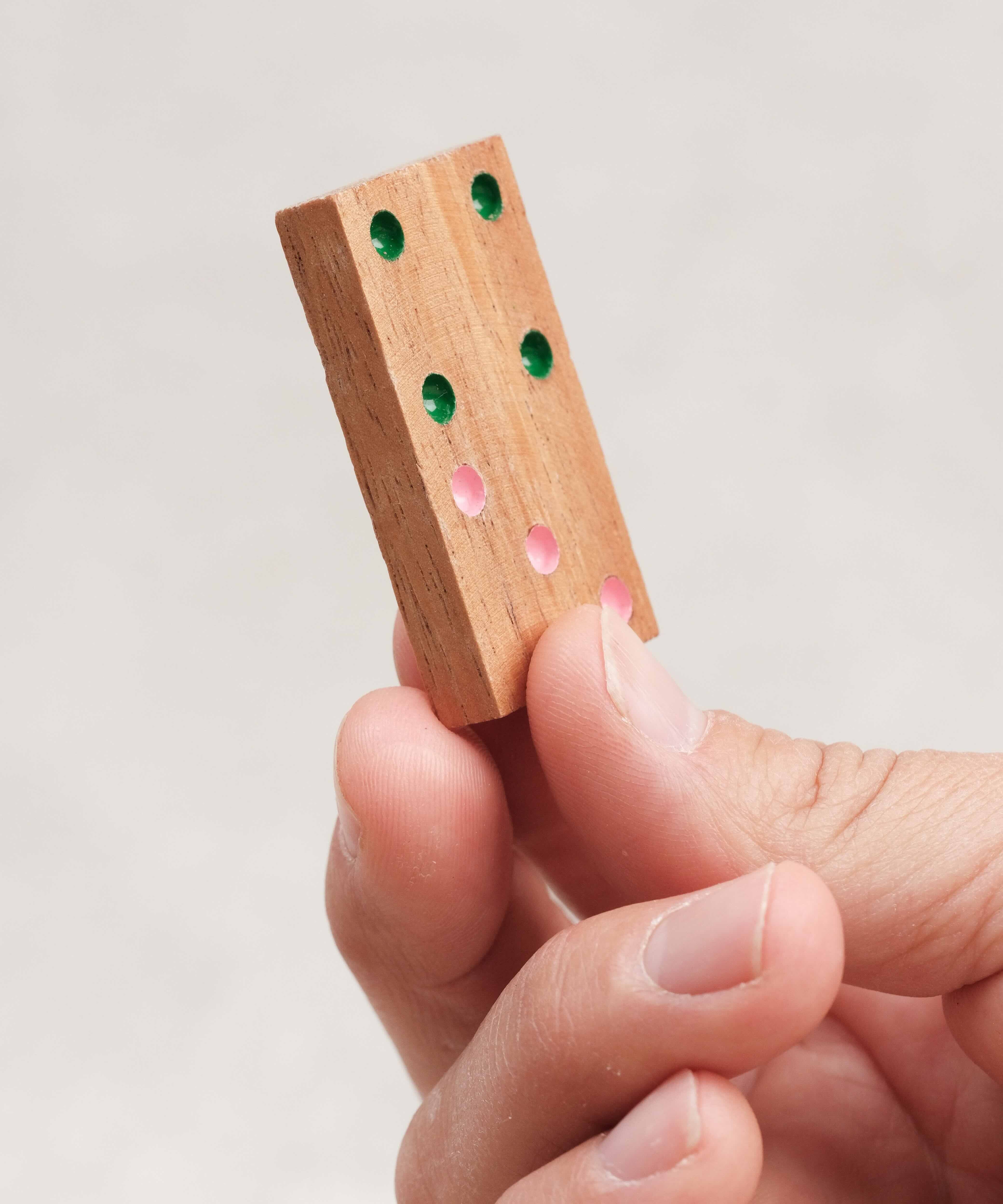 Pièce de domino en bois sérigraphié tenue en main