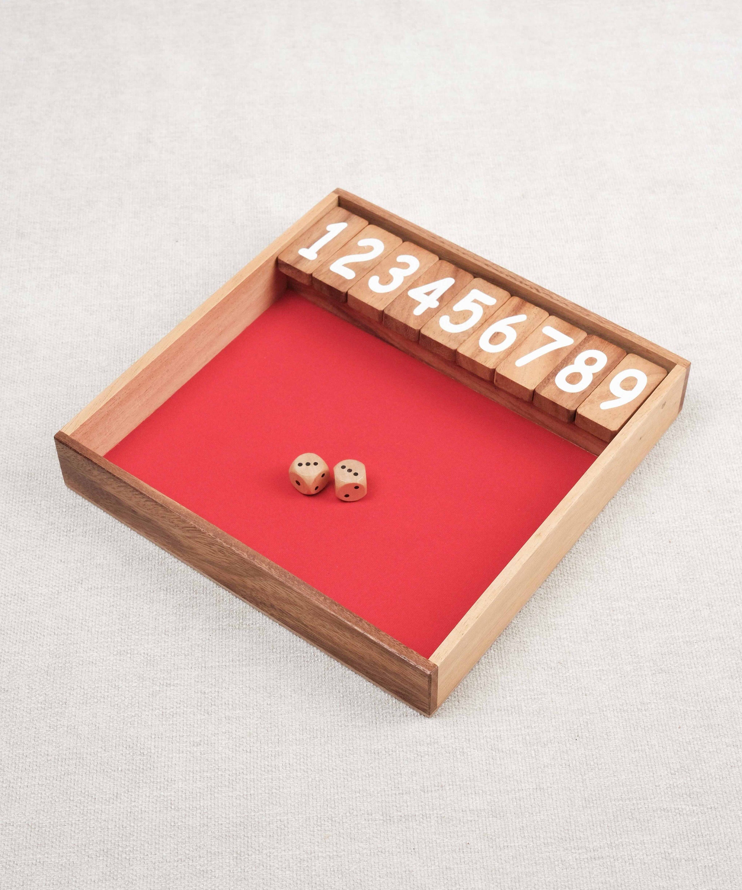 Plateau en bois du jeu Ferme la Boîte avec dés et chiffres numérotés.