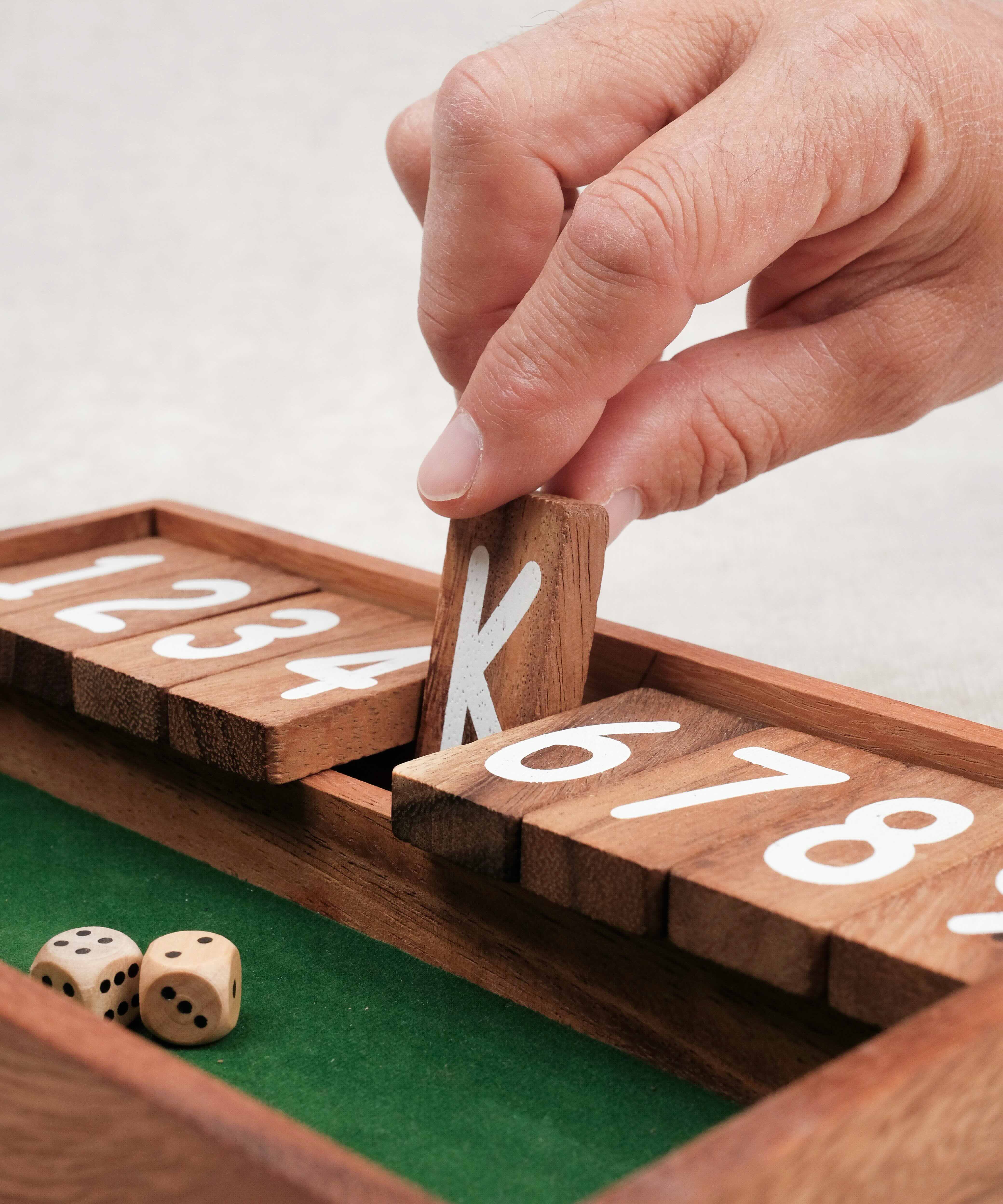 Main qui ferme une case numérotée sur le jeu Ferme la Boîte petit modèle.