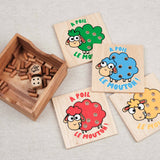 Coffret ouvert du jeu À Poil le Mouton avec plaquettes colorées et pions en bois.