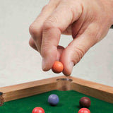 Main posant une bille colorée sur le mini billard