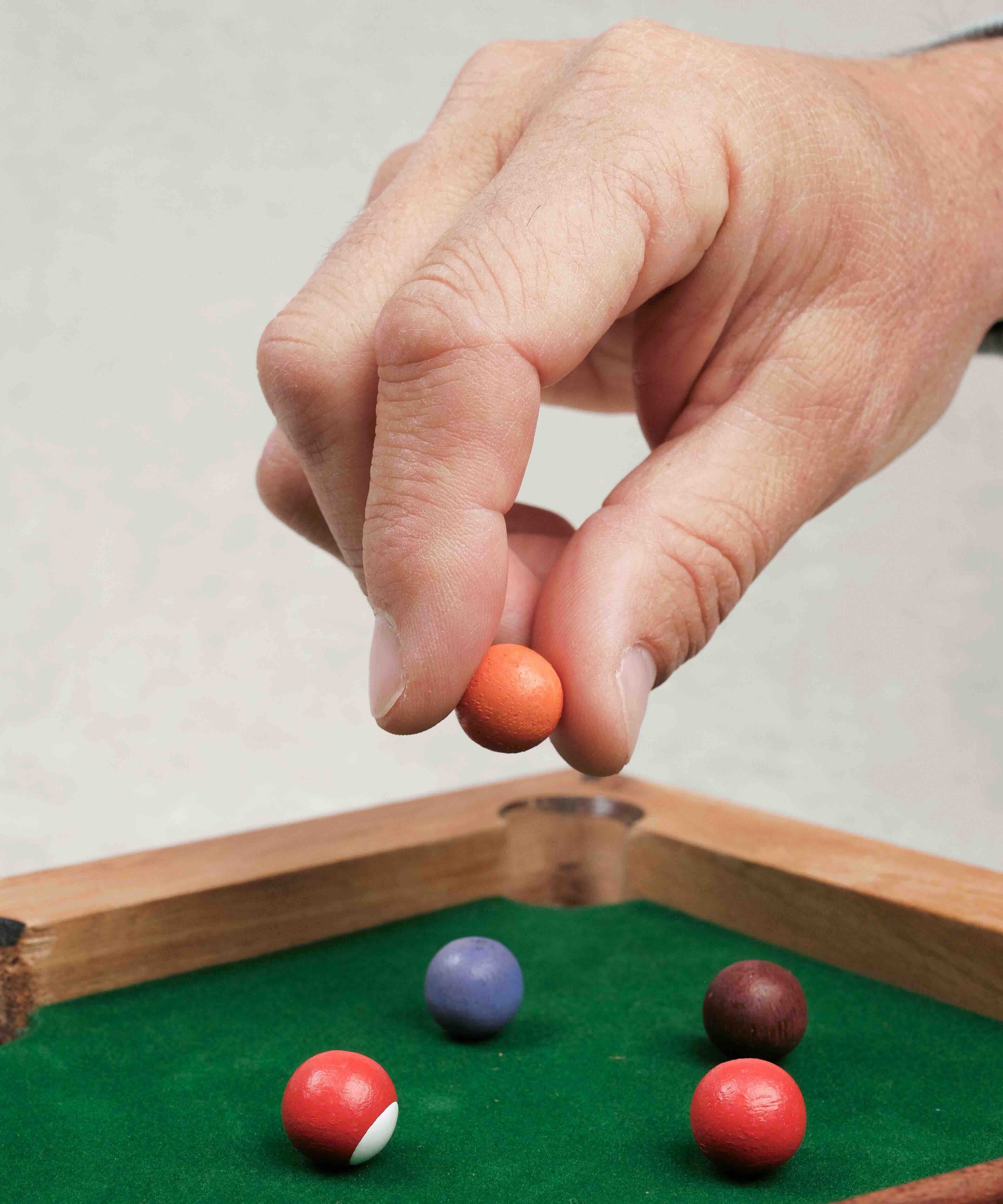 Main posant une bille colorée sur le mini billard