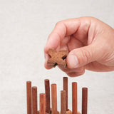 Main plaçant une croix en bois sur le plateau Morpion 3D M